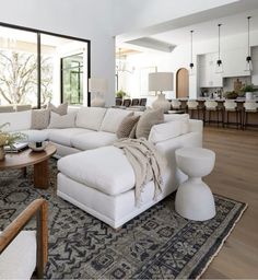 a living room filled with white furniture and lots of pillows on top of a rug