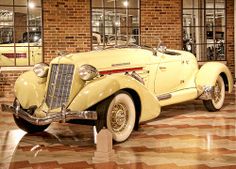 an old yellow car is parked in front of a brick building with large glass windows