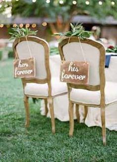 two chairs with signs on them are sitting in the grass at an outdoor wedding reception