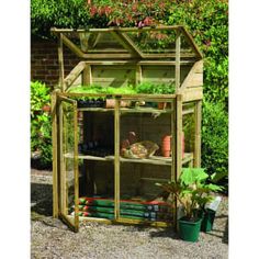 a small wooden greenhouse with plants growing inside