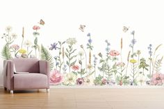 an empty chair in front of a wall with flowers and butterflies painted on the walls