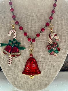 a necklace with two bells and candy canes on the front, one is red