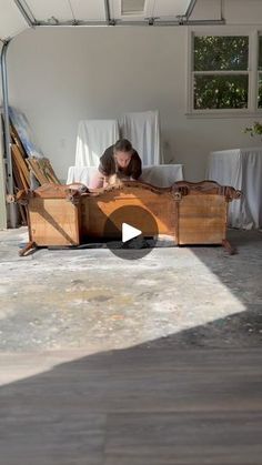 a woman laying on top of a wooden bed in a room with white sheets and curtains