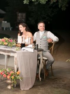 a man and woman sitting at a table with flowers