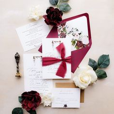 the wedding stationery is laid out on top of each other, with red and white flowers