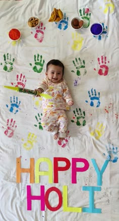 a baby laying on top of a white blanket covered in handprints and letters