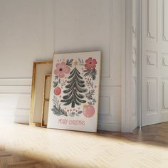 a framed christmas card sitting on the floor next to an empty frame with a tree in it