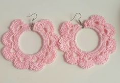 two pink crocheted hoop earrings on a white surface