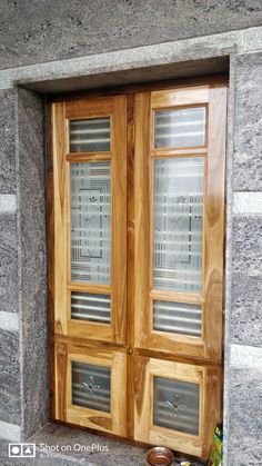 an open wooden door with glass panels on the front and side windows in between two stone walls