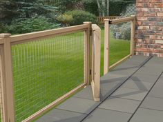 a fenced in area with green grass and brick wall next to the walkway leading up to it