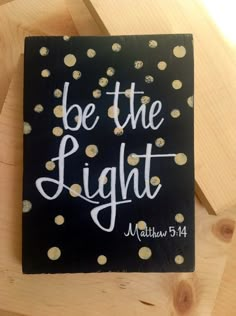 a bible with the words be the light written on it and gold dots in white