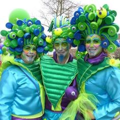 three people dressed in green and blue are posing for the camera with their faces painted like peacocks