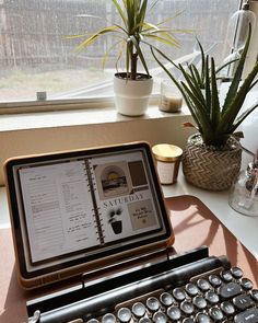 an old fashioned typewriter sitting on top of a table next to a potted plant