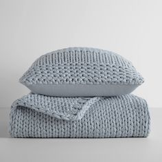 two pillows and a blanket on top of each other, one is blue in color