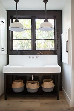 a white sink sitting under two lights in a bathroom