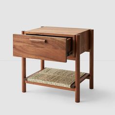 the side table has two drawers and one drawer with a woven seat pad on it