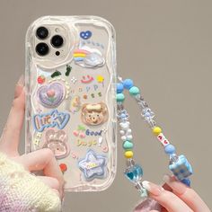 a person holding up a phone case with various stickers and beads attached to it