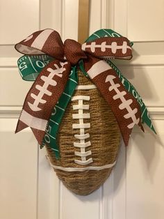 a football ornament hanging on the front door with a green and white ribbon