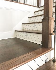 an empty staircase with wooden handrails and white painted walls in a home setting