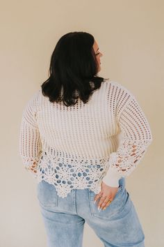 a woman in jeans and a white sweater is looking down at the back of her body