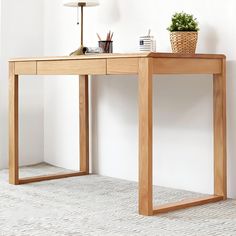 a wooden desk with a potted plant sitting on it's side and a lamp next to it