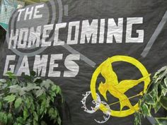 a banner that says the home coming games with a bird on it in front of some plants