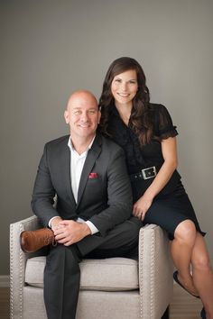 a man and woman sitting on a chair posing for the camera with their arms around each other