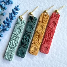 three pairs of earrings are shown next to each other on a table with blue flowers