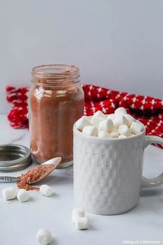 two mugs filled with marshmallows on top of a white countertop