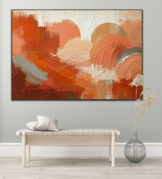 an abstract painting hangs on the wall above a bench and vase with flowers in it