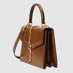 Description Designed with its original archetype in mind, the Sylvie 1969 unifies the details of its archival inspiration with a contemporary spirit. The structured top handle in textured brown leather is defined by a narrow gold-toned metal chain fitted to the flap and body of the bag—a modern interpretation of the distinctive hardware. The silhouette is completed with a detachable and adjustable shoulder strap. Size: 10.2″W x 7.7 “H x 3.3 “D / 25.9 x 19.5 x 8.3 cm 100% genuine materials, matching the quality of the Gucci product (imported from Europe); Brown textured leather with a vintage effect Shiny gold-toned hardware Leather lining Metal chain and buckle closure Exterior back pocket Two interior gussets One interior zipper and one interior open pocket top handle with 4.3″ drop Detac Gucci Top Handle Bag, Small Top Handle Bag, Gucci Sylvie, Structured Top, Gucci Store, Gucci Gifts, Pocket Top, Handle Bag, 7 H