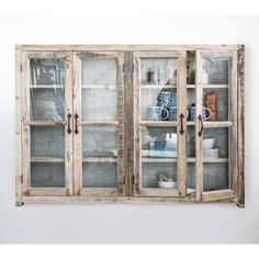 an old wooden cabinet with glass doors on the front and bottom, is displayed against a white wall