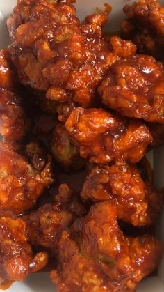 a white bowl filled with chicken wings covered in sauce