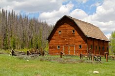 an old wooden barn in the middle of a field