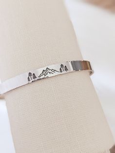 "Mountain cuff, tree cuff bracelet, Hand stamped, Outdoors gift, Bracelet for her, Hiking gift, Inspirational, Motivational, Encouragement gift, Personalized, Customized This listing is for ONE polished Aluminum cuff bracelet. Perfect for the outdoors lover - makes a wonderful and thoughtful gift. The bracelet is stamped by hand with steel stamps and a hammer, no engraving. The front is stamped with a mountain and trees and the ends can be personalized for an extra meaningful piece. The bracelet Tree Cuff, Gift Tree, Encouragement Gift, Mountain Forest, Hiking Gifts, Gift Bracelet, Encouragement Gifts, Outdoor Lover, Outdoor Gift