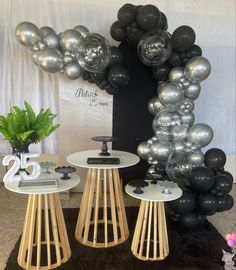 two tables with black and silver balloons on them