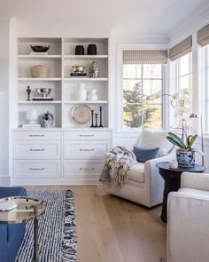 a living room filled with white furniture and lots of shelves full of dishes on top of them