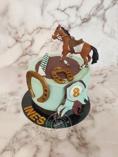 a birthday cake with a horse on top and horseshoes in the shape of numbers