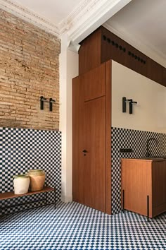 a bathroom with black and white checkered tile on the floor, wooden cabinet, and sink