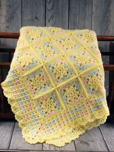 a yellow crocheted blanket sitting on top of a wooden bench