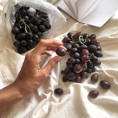 a person reaching for grapes on a bed