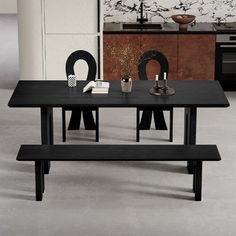 a black table and bench in a room with white walls, flooring and cabinets