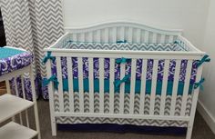 a white crib with blue and gray bedding