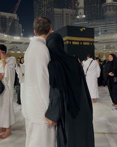 two men dressed in black and white are standing near the ka'bah at night