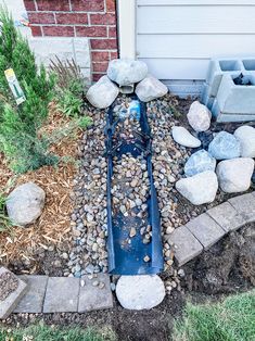 a garden with rocks and gravel in front of a house