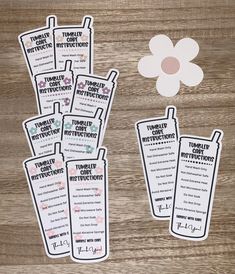 several tags with instructions on them sitting on a wooden table next to a paper flower