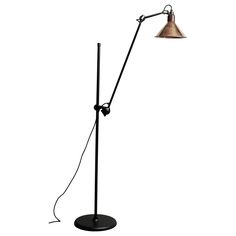 a black floor lamp with a metal shade on it's arm and a white background