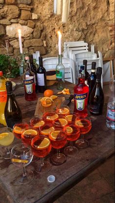 a table topped with lots of glasses filled with oranges and drinks next to bottles