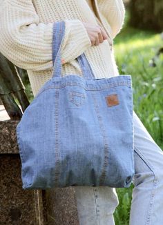 a woman sitting on a bench holding a large blue tote bag in her hands