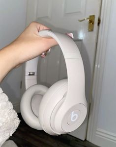 a woman is holding up her headphones in front of the door with it's arm